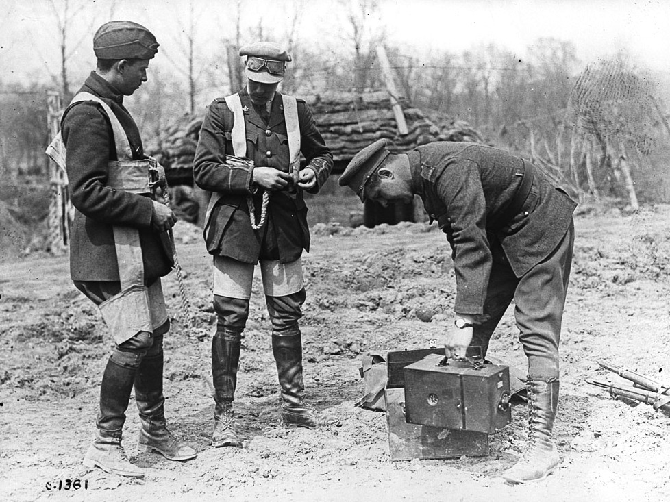 World War I kite balloon operators wearing parachutes and preparing photographic equipment before an observation ascent, May 1917.