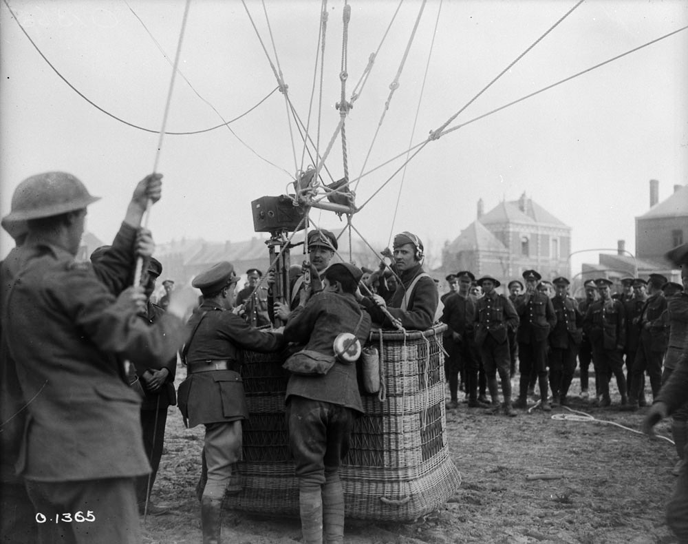 World War I kite balloon being prepared for launch as a Canadian kinematographer stands in the basket, surrounded by ground crew and tether lines, May 1917.