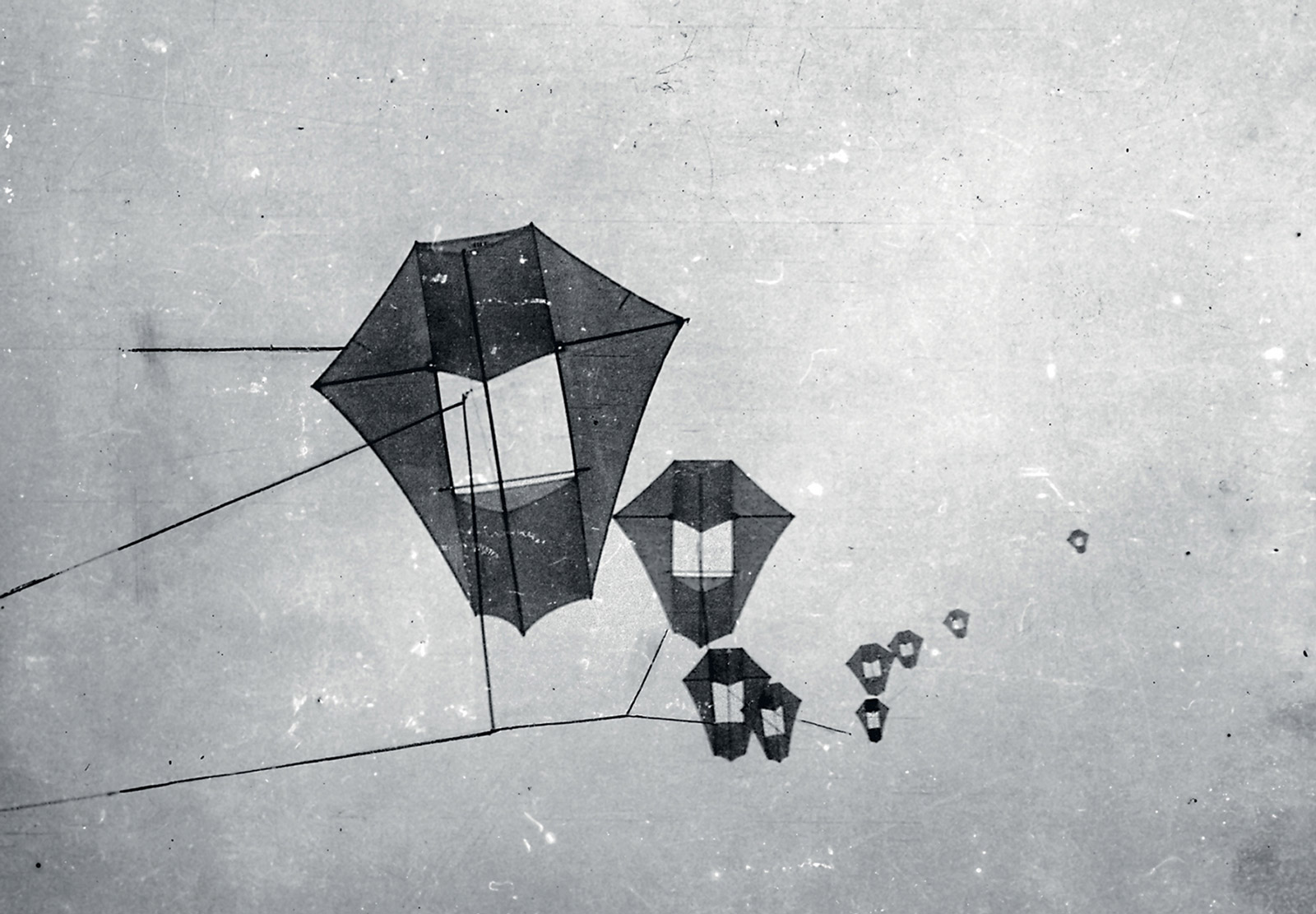 A train of multiple kites flying in sequence, used to lift a heavy aerial camera.