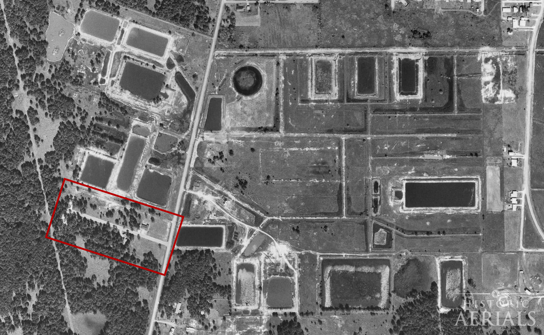 1966 aerial image showing residential street development adjacent to active oil storage pits in Humble, Texas.